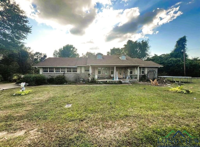 single story home featuring a trampoline, a front yard, and a porch