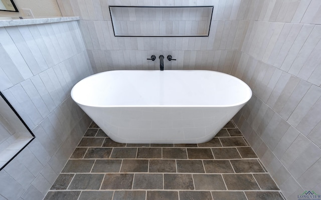 bathroom featuring tile walls, a bath, and tile patterned floors