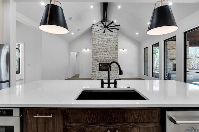 kitchen featuring light stone countertops, sink, a fireplace, and decorative light fixtures