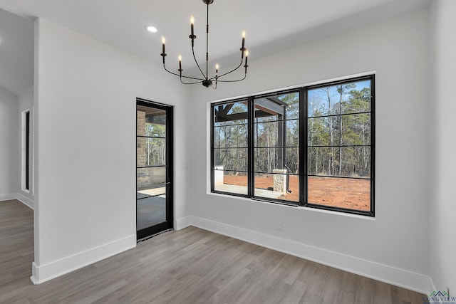 unfurnished dining area featuring an inviting chandelier and light hardwood / wood-style flooring