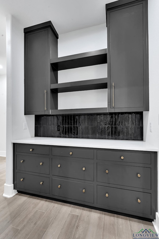 kitchen featuring backsplash, light hardwood / wood-style flooring, and gray cabinetry