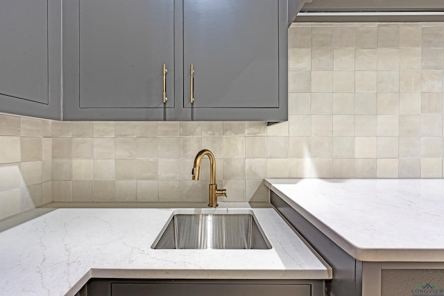 kitchen featuring gray cabinets, sink, light stone counters, and decorative backsplash