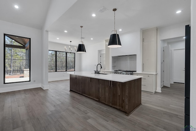 kitchen featuring a large island, sink, pendant lighting, light hardwood / wood-style flooring, and white cabinets