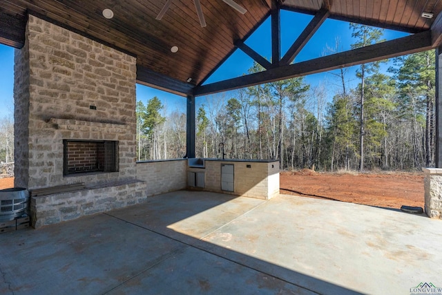 view of patio / terrace featuring ceiling fan, exterior kitchen, and an outdoor stone fireplace