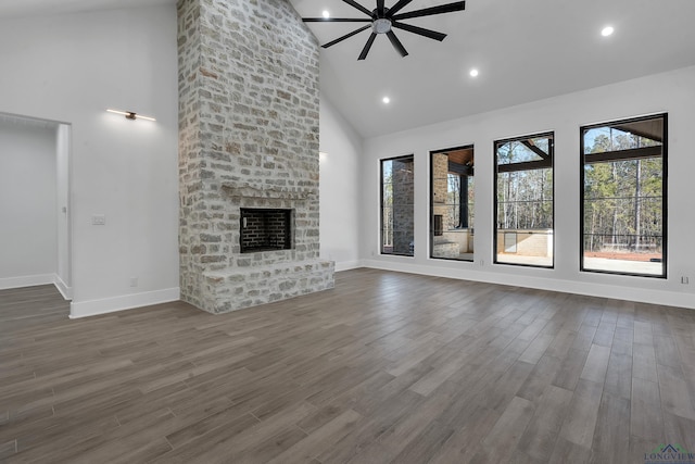 unfurnished living room with a stone fireplace, wood-type flooring, high vaulted ceiling, and ceiling fan