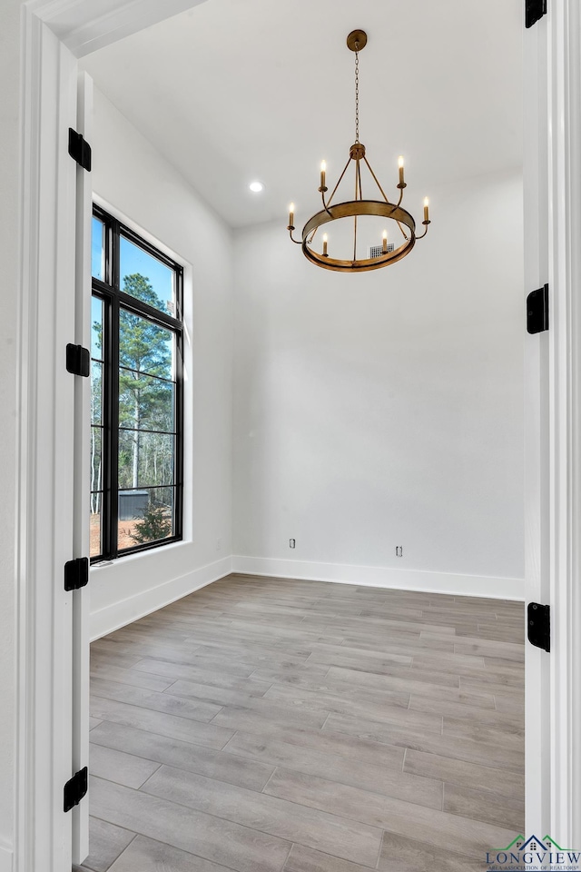 unfurnished room featuring light hardwood / wood-style floors and a chandelier