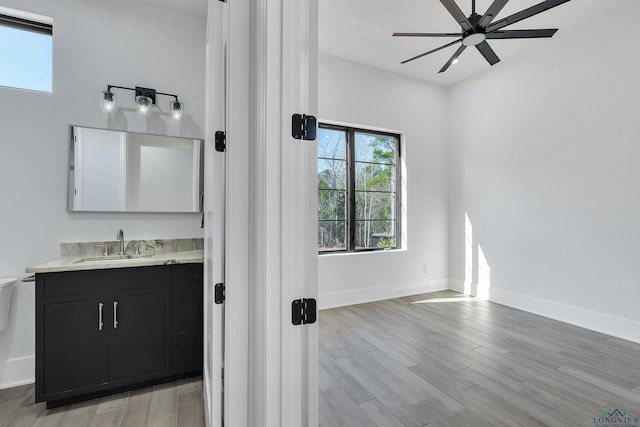 bathroom with wood-type flooring, vanity, ceiling fan, and toilet