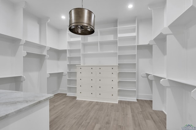 walk in closet with light hardwood / wood-style floors