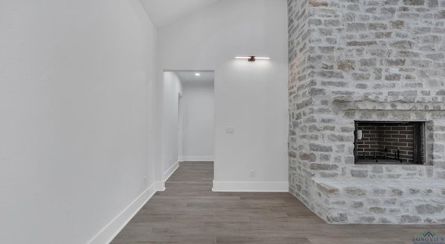 unfurnished living room featuring lofted ceiling, hardwood / wood-style floors, and a brick fireplace