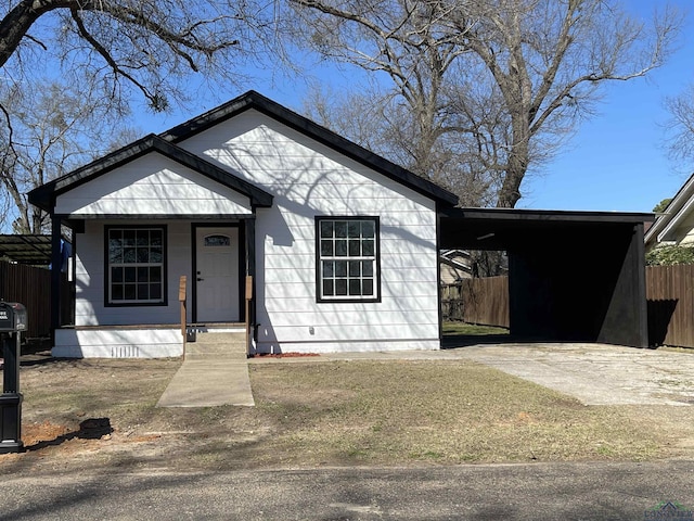 view of front of property with fence, a carport, and concrete driveway