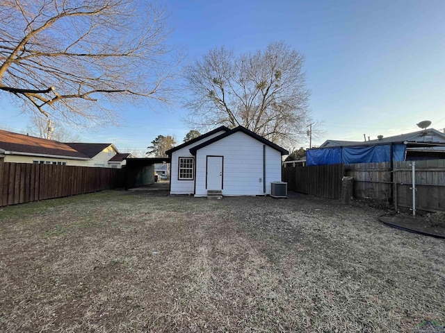 exterior space with central air condition unit, a fenced backyard, and an outdoor structure