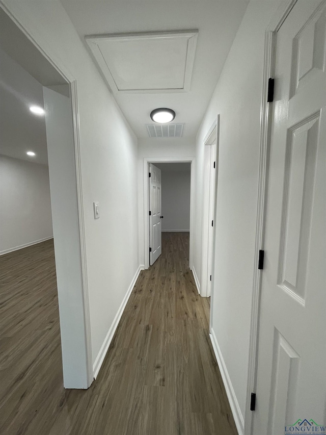 hall with dark wood-style floors, attic access, visible vents, and baseboards