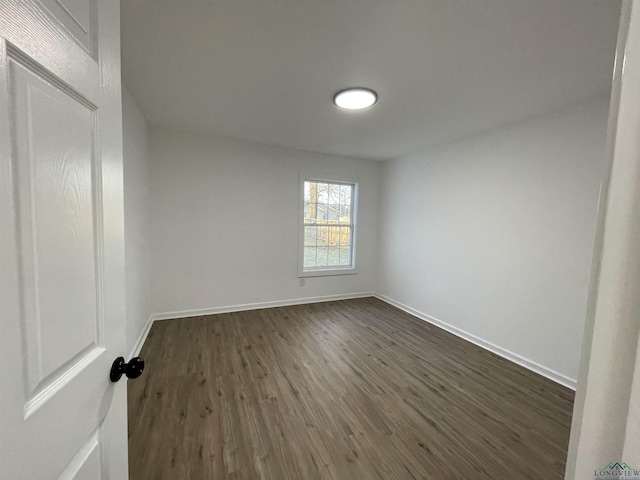 empty room with dark wood finished floors and baseboards