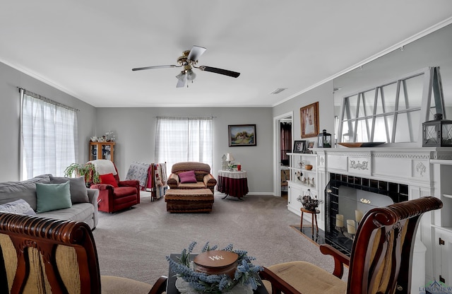 carpeted living room with ceiling fan, crown molding, and a tile fireplace