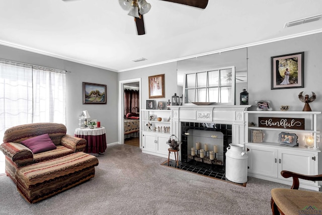 carpeted living room with ceiling fan, a fireplace, and crown molding