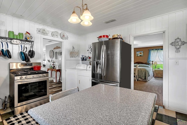 kitchen with wood ceiling, washing machine and dryer, pendant lighting, and stainless steel appliances