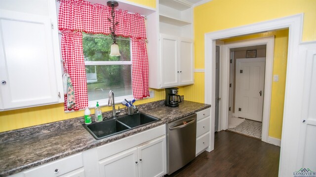 kitchen with white cabinetry, a sink, dark countertops, dishwasher, and dark wood finished floors