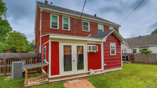back of property featuring a fenced backyard, cooling unit, a lawn, brick siding, and french doors