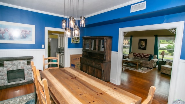 dining room with wood finished floors, visible vents, crown molding, and wainscoting