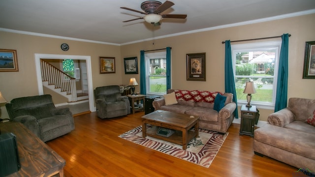 living room with wood finished floors, ceiling fan, ornamental molding, and a healthy amount of sunlight