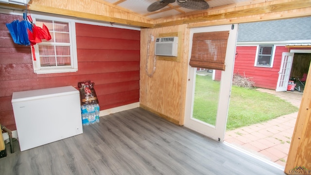 interior space featuring wood finished floors, wood walls, a wall mounted AC, a ceiling fan, and lofted ceiling
