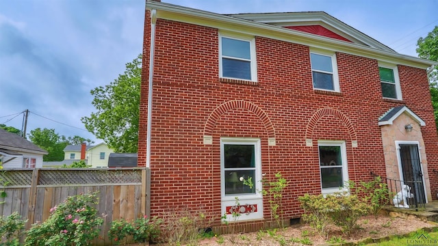 view of front of house featuring brick siding and fence