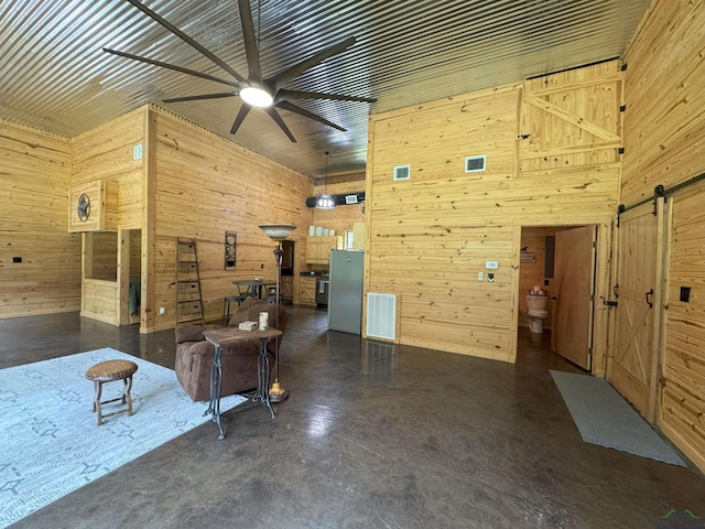 226 Almand, Waskom, TX 75692 - living area featuring finished concrete flooring, wood walls, a barn door, and ceiling fan