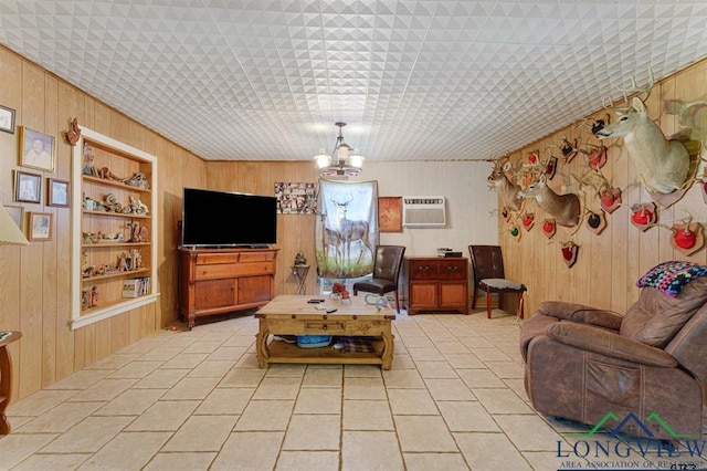 living room with light tile patterned flooring, wood walls, a wall mounted air conditioner, built in features, and a notable chandelier