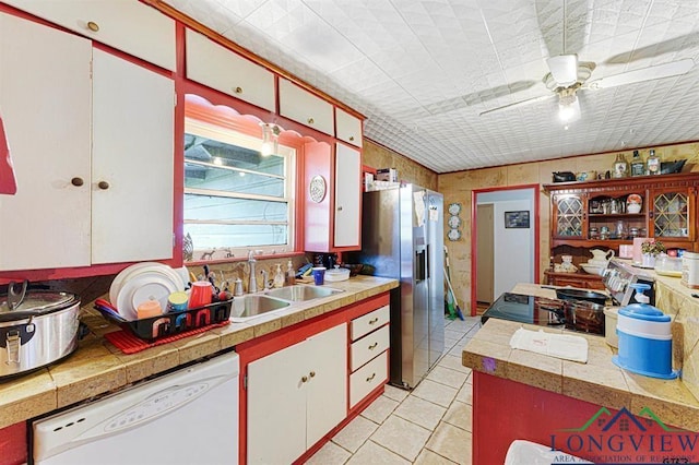 kitchen featuring sink, light tile patterned floors, ceiling fan, white dishwasher, and white cabinets