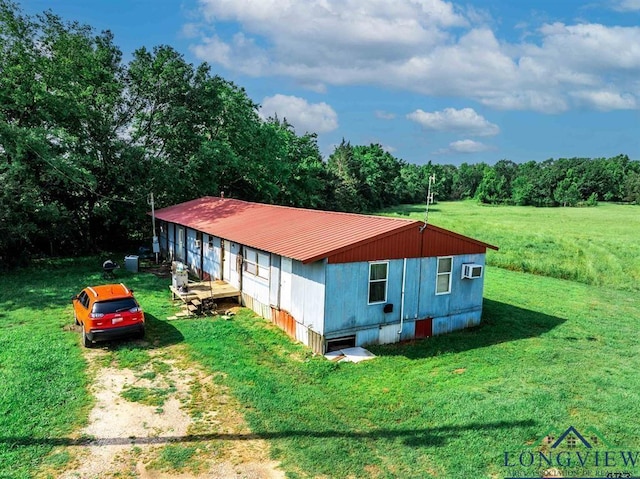 view of side of property featuring a lawn and a wall mounted AC