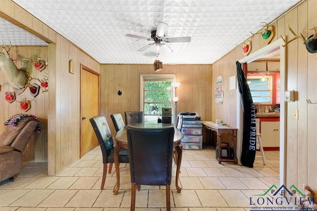 tiled dining room featuring ceiling fan and wooden walls