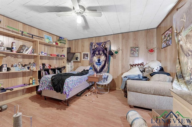 bedroom featuring wooden walls, light hardwood / wood-style floors, and ceiling fan