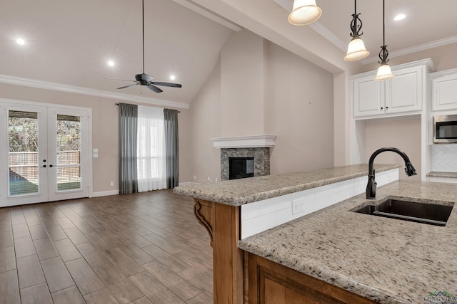 kitchen featuring light stone counters, ceiling fan, sink, decorative light fixtures, and white cabinetry