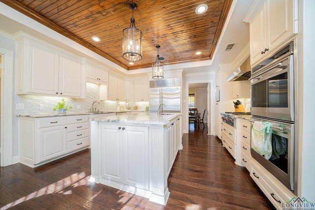 kitchen featuring pendant lighting, an island with sink, appliances with stainless steel finishes, tasteful backsplash, and white cabinetry