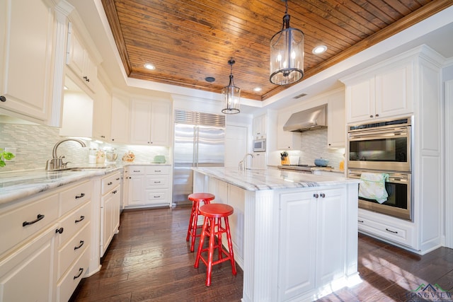 kitchen featuring a center island with sink, white cabinetry, wooden ceiling, and wall chimney range hood