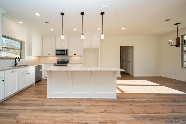 kitchen featuring light stone countertops, light hardwood / wood-style flooring, stainless steel appliances, and a kitchen island