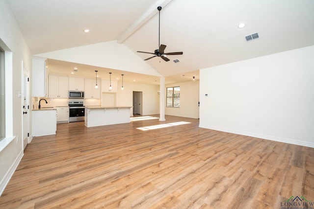 unfurnished living room featuring sink, ceiling fan, vaulted ceiling with beams, and light hardwood / wood-style flooring