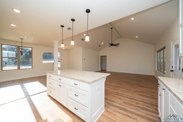 kitchen with white cabinetry, light stone counters, and hanging light fixtures