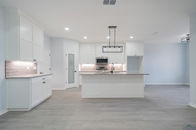 kitchen featuring appliances with stainless steel finishes, a center island with sink, and white cabinetry