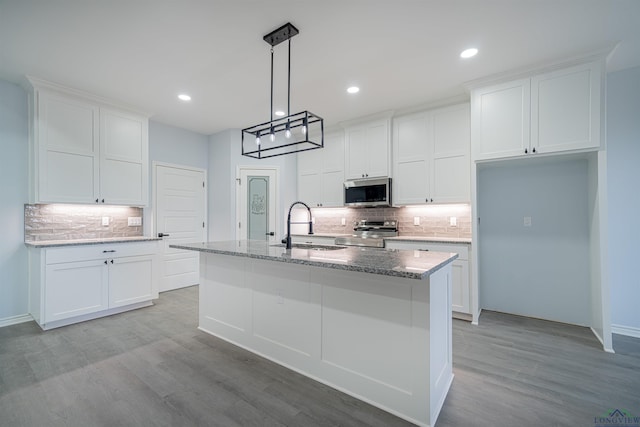 kitchen with a kitchen island with sink, white cabinets, sink, light hardwood / wood-style flooring, and appliances with stainless steel finishes