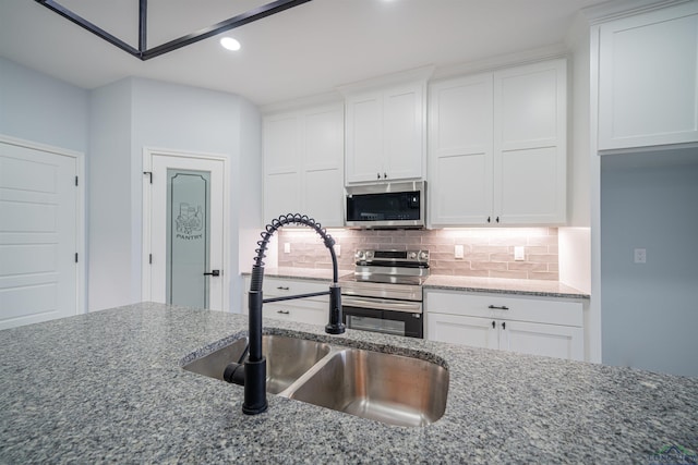 kitchen with light stone countertops, sink, white cabinets, and appliances with stainless steel finishes