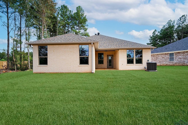 back of house with central AC unit and a yard