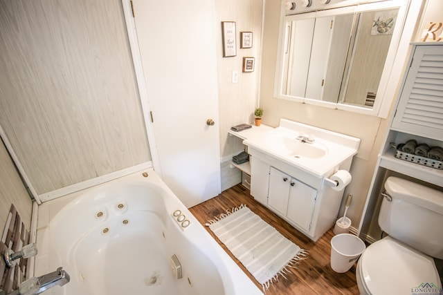 full bathroom with a tub with jets, wood finished floors, toilet, and vanity