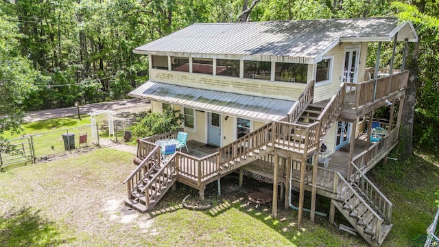 back of property featuring stairway, a deck, metal roof, and a gate