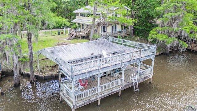 dock area with stairway, fence, a deck with water view, and a yard