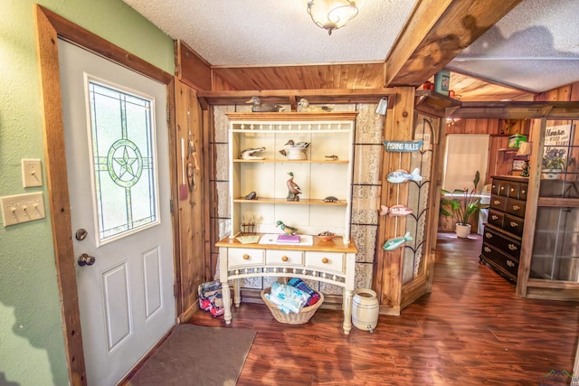 foyer with a textured ceiling, wooden walls, and wood finished floors