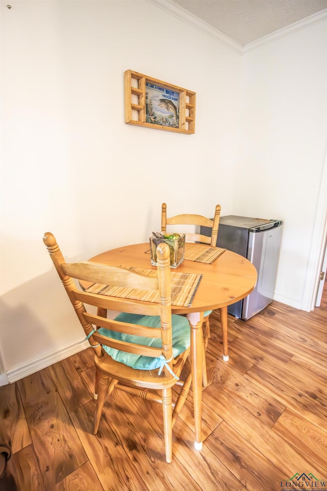 dining room featuring baseboards, ornamental molding, and light wood-style floors