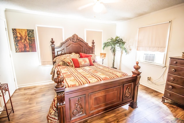 bedroom featuring light wood finished floors, ceiling fan, cooling unit, crown molding, and a textured ceiling