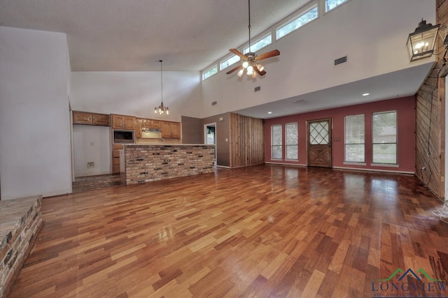 324 Highlander Hts, Hideaway, TX 75771 - unfurnished living room featuring wood finished floors, a towering ceiling, ceiling fan, healthy amount of natural light, and a chandelier