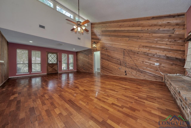 324 Highlander Hts, Hideaway, TX 75771 - unfurnished living room with wood walls, wood finished floors, plenty of natural light, a towering ceiling, and ceiling fan